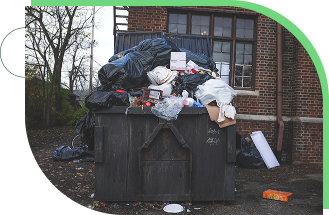 A dumpster full of trash next to a building.