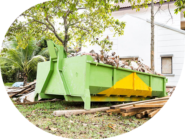 A green dumpster with many pieces of wood in it.