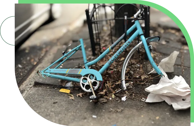 A bicycle laying on the ground near a trash can.